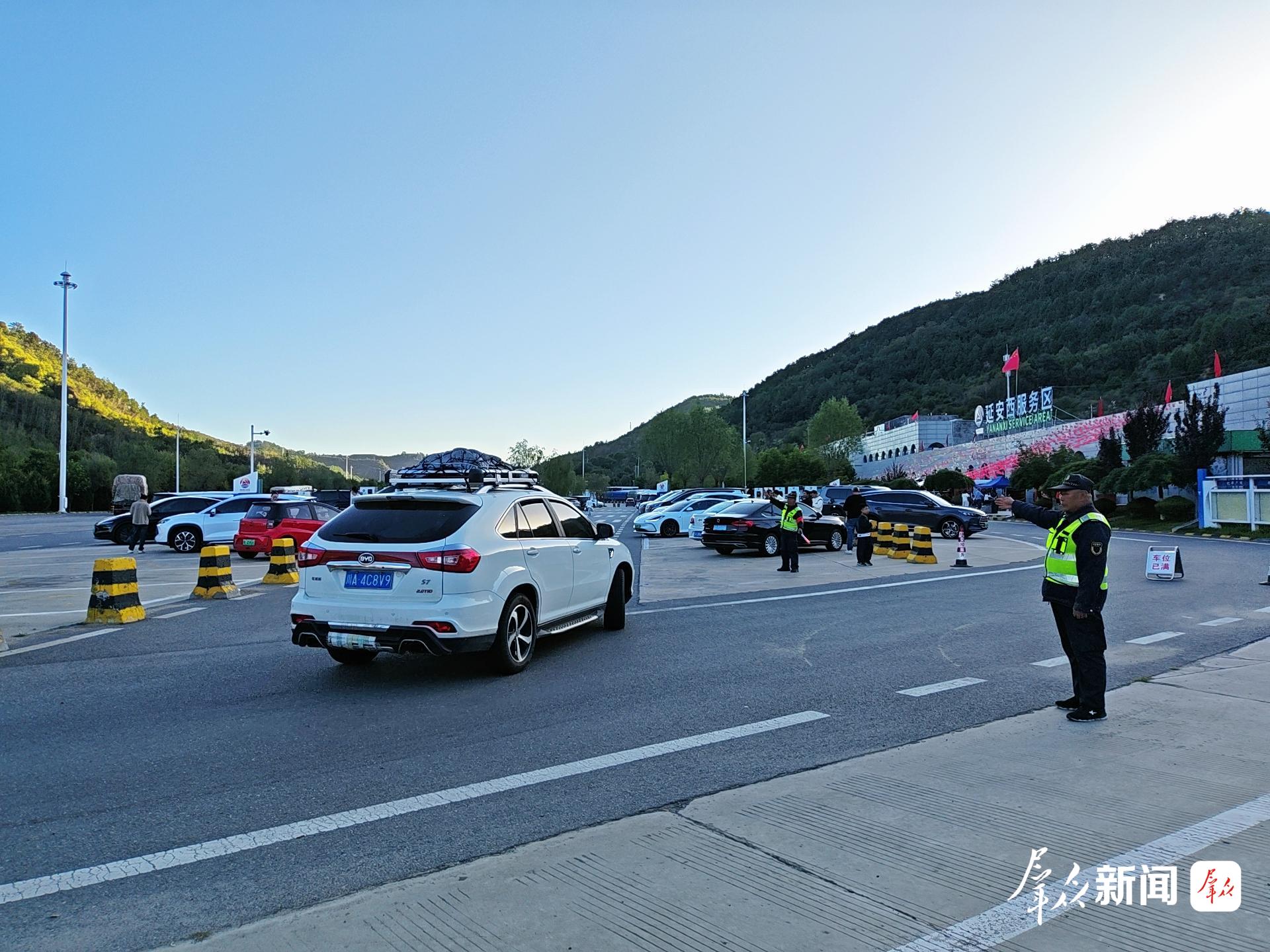 10 月1日,国庆节假期首日,包茂高速延安西服务区迎来客流高峰。图为工作人员指引车辆有序进入停车区停放。
